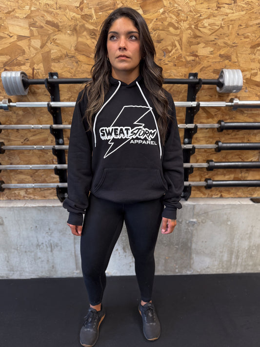Woman wearing a black hoodie with 'Sweat Storm Apparel' logo in a gym setting